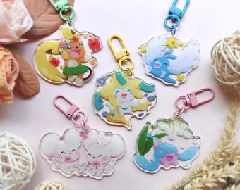 May include: A collection of colorful acrylic keychains featuring various cartoon characters. Each keychain has a unique design with vibrant colors and attached metal clasp. The keychains are in various shapes and sizes, with a clear, glossy finish.