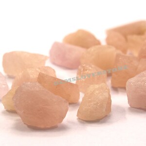 Pode incluir: Uma cole&ccedil;&atilde;o de gemas brutas rosa e laranja. As pedras s&atilde;o de v&aacute;rios tamanhos e formas, algumas tendo uma apar&ecirc;ncia mais transl&uacute;cida do que outras.