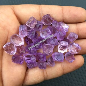 May include: A pile of small, rough, purple amethyst crystals. The crystals are translucent and have a variety of shapes and sizes.