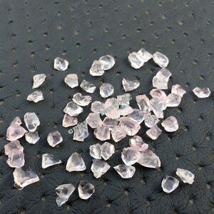 Pode incluir: Uma coleção de pequenos cristaux de quartzo rosa cor de rosa. Os cristais são ásperos e têm um aspecto natural não polido.