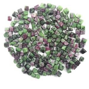 May include: A pile of small, green and pink, faceted gemstone beads. The beads are roughly square in shape and have a natural, rough texture.