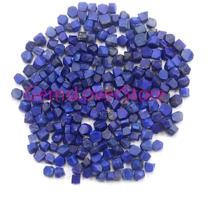 May include: A large pile of small, dark blue, faceted lapis lazuli gemstone chips. The chips are irregularly shaped and have a rough, natural texture.