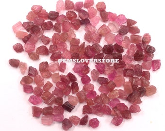 May include: A large pile of pink and red tourmaline rough gemstones. The rough gemstones are various shapes and sizes.