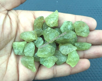 May include: A collection of small, rough, green gemstone chips. The chips are translucent and have a slightly irregular shape.
