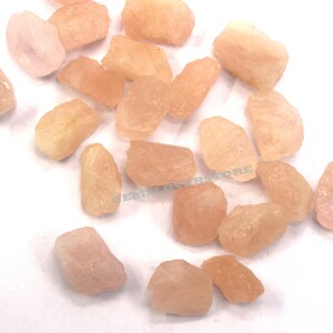 Pode incluir: Uma cole&ccedil;&atilde;o de gemas brutas rosa e laranja. As pedras s&atilde;o de v&aacute;rios tamanhos e formas, e t&ecirc;m um acabamento natural n&atilde;o polido.