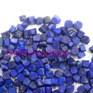 Könnte beinhalten: Ein großer Haufen kleiner, rauer, dunkelblauer Lapislazuli-Edelsteinchipse. Die Chips sind unregelmäßig geformt und haben einen leicht metallischen Glanz.