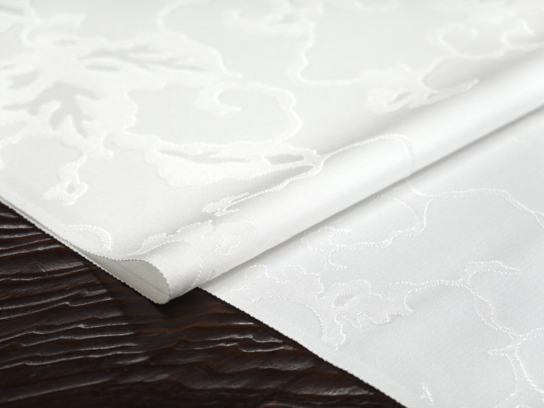 May include: White fabric with a subtle embossed pattern of clouds. The fabric is folded in half and the edges are visible.