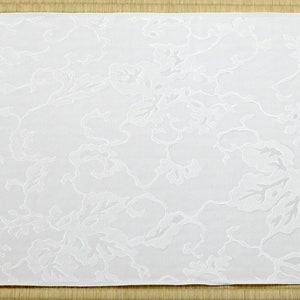 May include: White fabric with an embossed floral pattern. The fabric has a subtle texture and a delicate design.