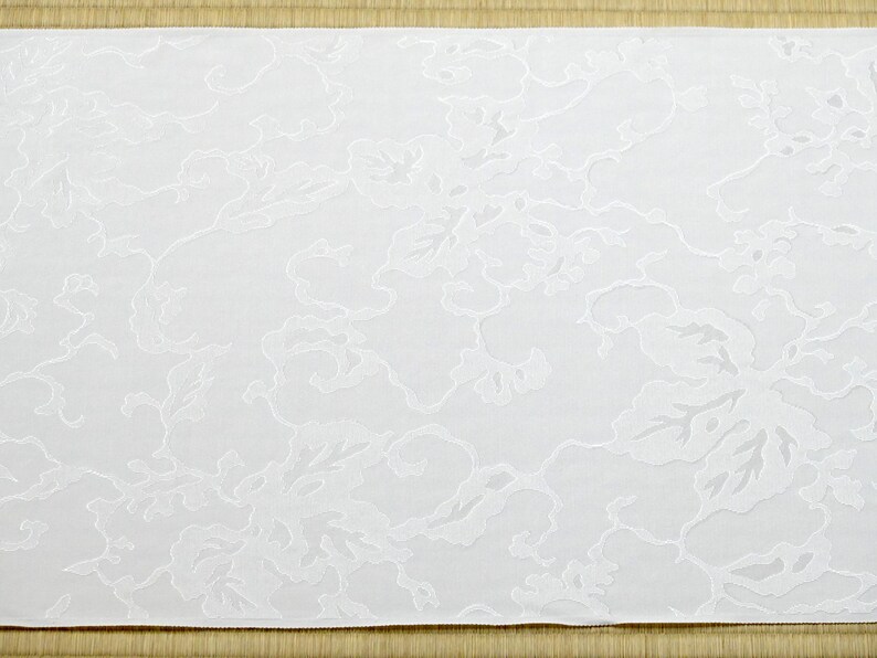 May include: White fabric with an embossed floral pattern. The fabric has a subtle texture and a delicate design.