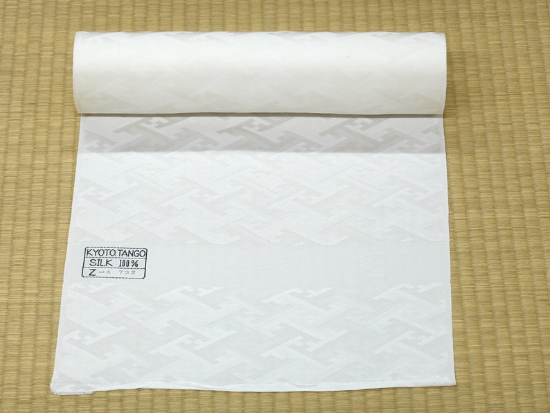 May include: A white fabric roll with a geometric pattern. The fabric is labeled "Kyoto Tango Silk 100% Z-A 732".