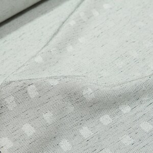 May include: Close-up of a white fabric with a subtle textured pattern. The fabric has a slightly grainy appearance and a subtle sheen.