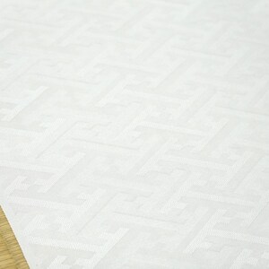 May include: White fabric with a subtle embossed pattern of repeating geometric shapes. The fabric has a smooth, slightly textured surface.