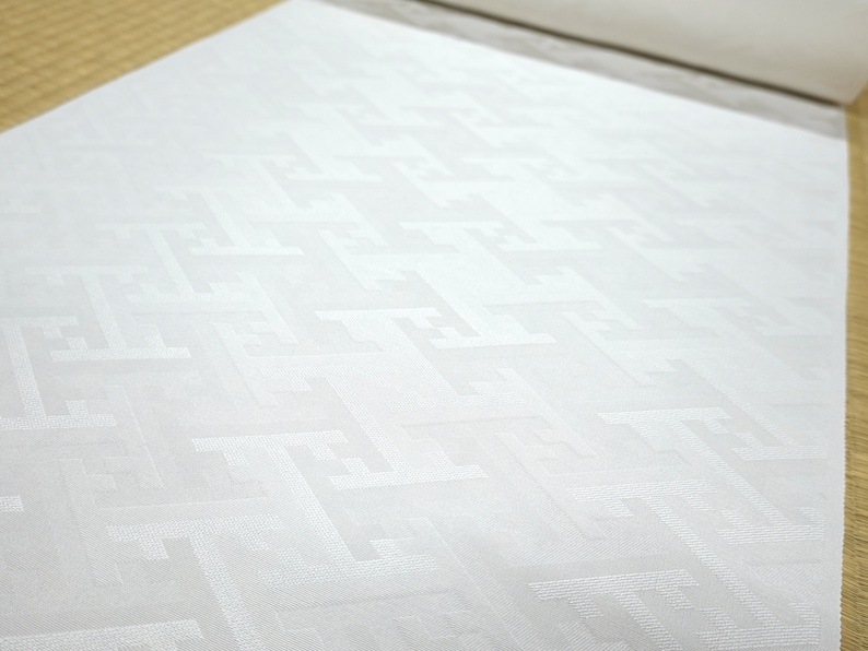 May include: White fabric with a subtle geometric pattern. The fabric has a smooth, silky texture.