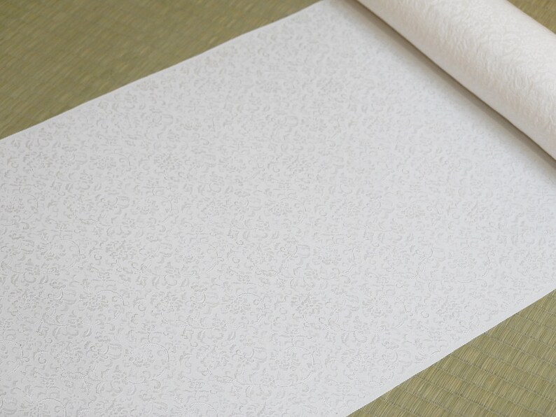 May include: A white roll of wallpaper with a subtle embossed pattern of small, swirling designs.