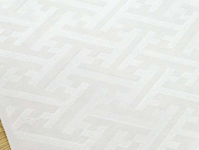 May include: White fabric with a geometric pattern of small squares and rectangles. The fabric has a subtle texture and a slightly off-white color.