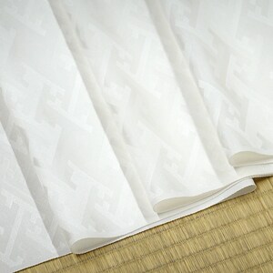 May include: White fabric with a subtle embossed pattern. The fabric is folded several times, revealing the pattern.