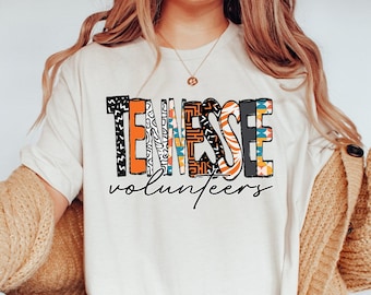 Op de afbeelding: Een wit T-shirt met een kleurrijk grafisch ontwerp waarop "TENNESSEE volunteers" staat. De grafiek is gemaakt van verschillende patronen en kleuren, waaronder oranje, zwart en wit.