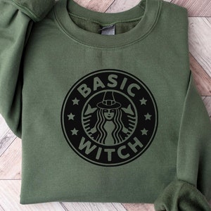 Könnte beinhalten: Ein grünes Sweatshirt mit einer schwarzen Grafik einer Hexe mit einer Hexenmütze und dem Text "BASIC WITCH" in einem Kreis.
