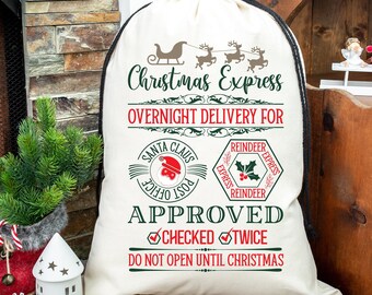 Puede incluir: Un saco de Santa de lona blanca con cordón de ajuste negro, con el texto "Christmas Express Overnight Delivery For" y un diseño de sello rojo y verde con el texto "Santa Claus Post Office" y "Reindeer Express".