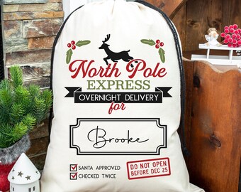 Puede incluir: Un saco de Santa de lona blanca con un cordón de ajuste negro. El saco tiene un gráfico rojo y negro que dice "North Pole Express Overnight Delivery for Brooke". Hay ramas de acebo verdes y una ilustración de reno. El saco también tiene una etiqueta roja y negra que dice "Do Not Open Before Dec 25".