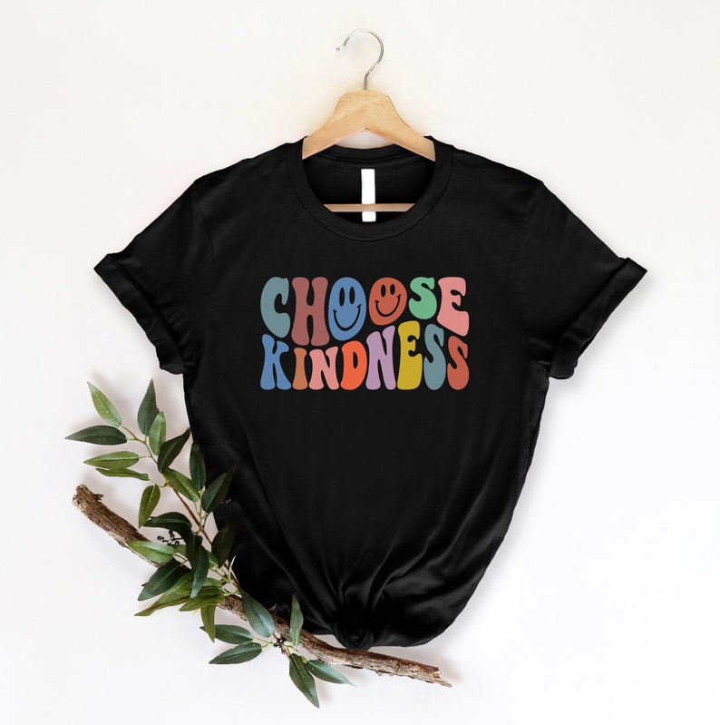 May include: Black t-shirt with a retro-style graphic that says "Choose Kindness" in rainbow colors with a smiley face in the "O" of "Choose".