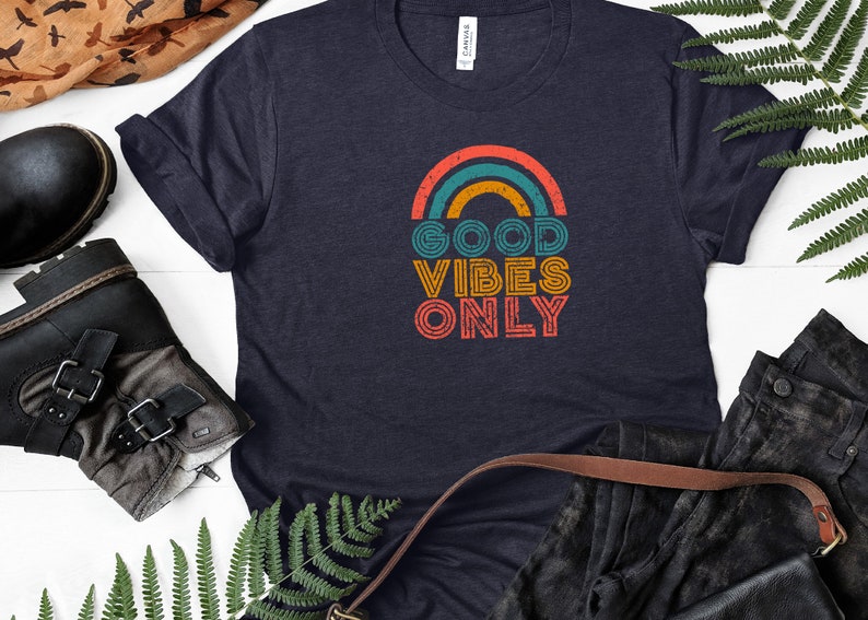 May include: A navy blue t-shirt with a rainbow graphic and the text "GOOD VIBES ONLY" in a vintage style font.