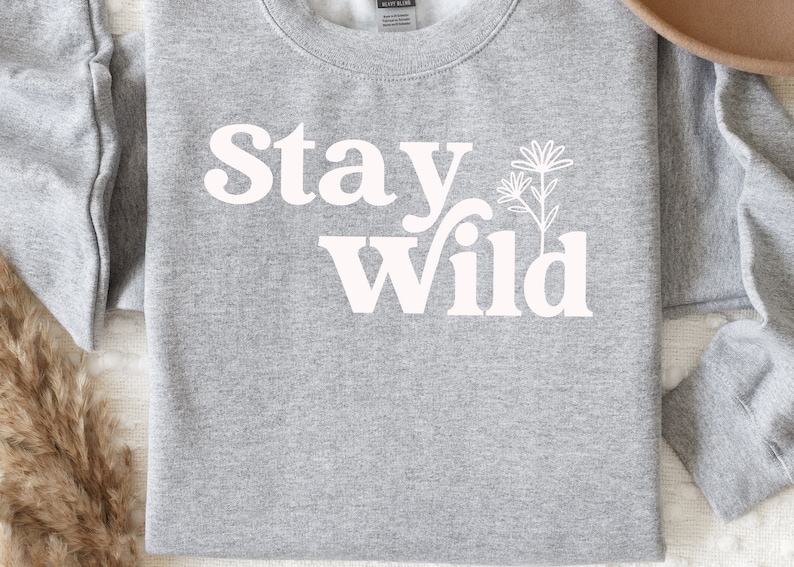 May include: Gray sweatshirt with white text that reads "Stay Wild" and a stylized flower graphic.
