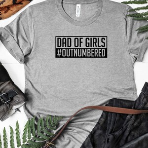 May include: Gray t-shirt with black text that reads "Dad of Girls #Outnumbered".