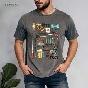 May include: A gray t-shirt with a humorous graphic of a dad doing various activities, including fishing, barbecuing, and mowing the lawn. The text on the shirt reads "Awesome Dad Ever #1 Dad Fit Dad, Barbecue, Mr. Fix It All, Dad Bop, I'm Sexy and I Mow It."