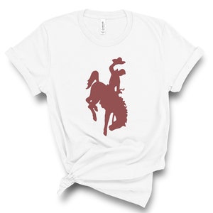 May include: White t-shirt with a maroon silhouette of a cowboy riding a bucking horse.