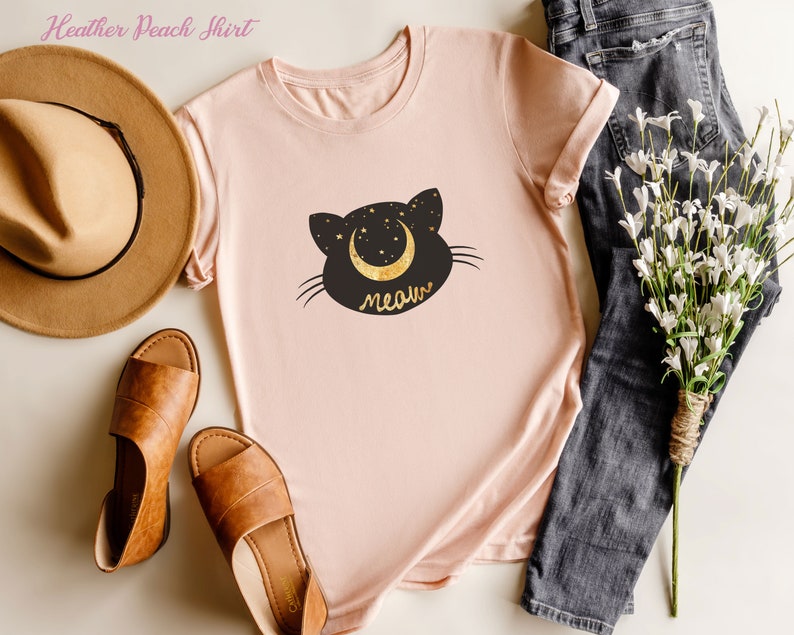 May include: A heather peach t-shirt with a black cat silhouette and a crescent moon with stars. The text "meow" is written below the cat.