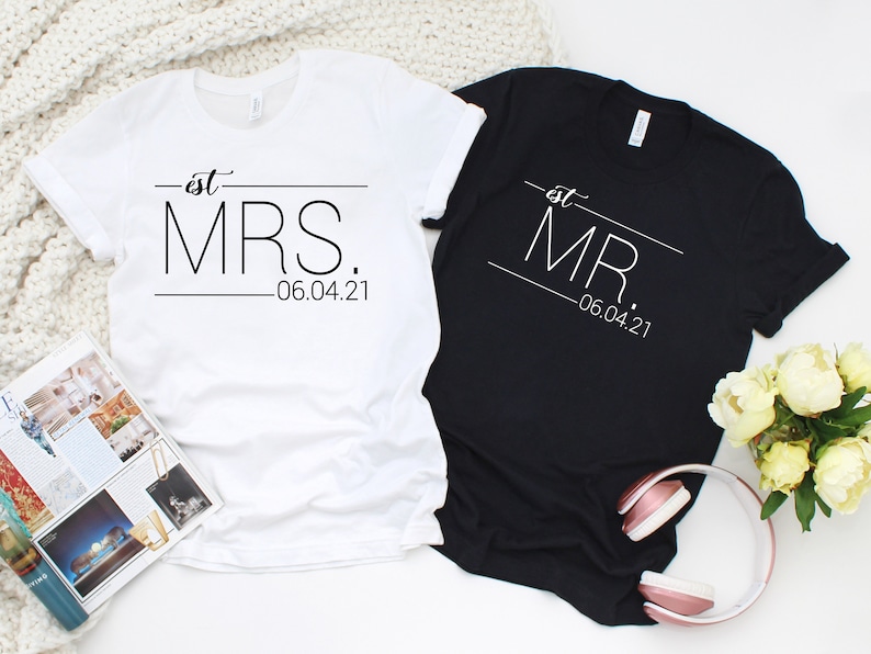 May include: Two white t-shirts with black text. The left shirt says "est. MRS. -06.04.21". The right shirt says "est. MR. -06.04.21".