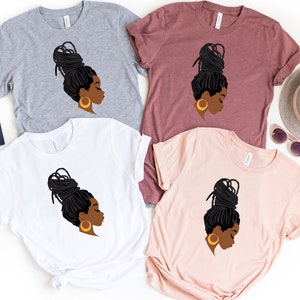 Puede incluir: Cuatro camisetas con un gr&aacute;fico de una mujer con un mo&ntilde;o de rastas y pendientes de aro dorados. Las camisetas son de color gris, granate, blanco y rosa.