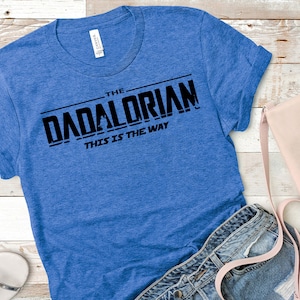 May include: A blue t-shirt with black text that reads "The Dadalorian This is the Way".