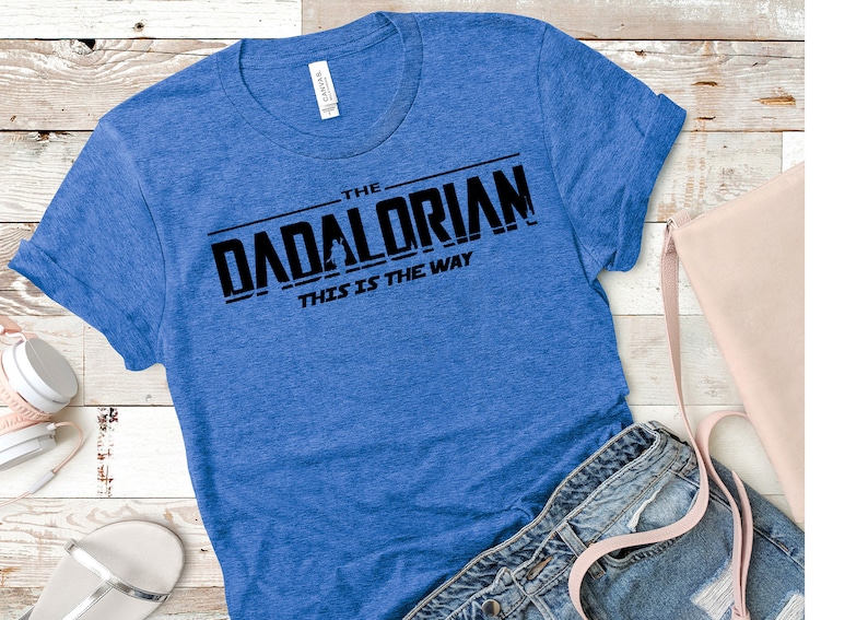 May include: A blue t-shirt with black text that reads "The Dadalorian This is the Way".