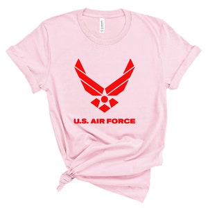 May include: Pink t-shirt with a red U.S. Air Force logo and the words "U.S. Air Force" printed on the front.