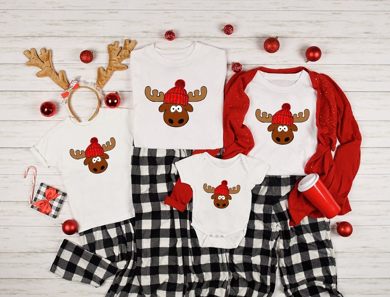 May include: A family of four matching pajamas with a red and white plaid pattern. Each pajama top features a white moose with a red Santa hat. The pajamas are perfect for a festive Christmas celebration.