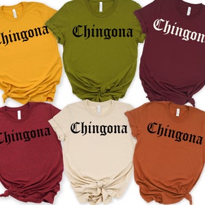 May include: Six t-shirts in different colours with the word "Chingona" printed in black gothic font.