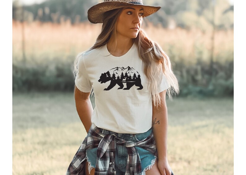 May include: White t-shirt with a black silhouette of a bear with mountains and trees inside the bear's body.
