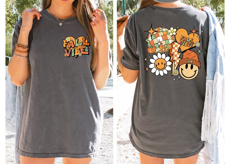 May include: A gray oversized t-shirt with a graphic print on the front that says "Fall Vibes" in a heart shape and a graphic print on the back that includes a smiley face flower, a disco ball, a pumpkin, a lightning bolt, and a smiley face wearing a beanie.