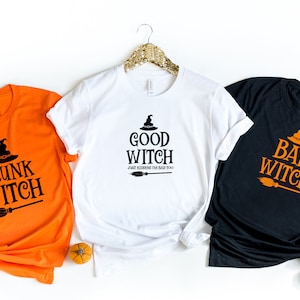 May include: Three t-shirts with different Halloween-themed designs. The first shirt is orange with the text "Drunk Witch" and a black witch's hat and broom. The second shirt is white with the text "Good Witch Just Kidding I'm Bad Too" and a black witch's hat and broom. The third shirt is black with the text "Bad Witch" and an orange witch's hat and broom.