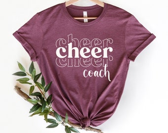 May include: A maroon t-shirt with the text "cheer cheer cheer coach" in white.