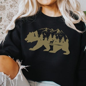 May include: A black sweatshirt with a brown silhouette of a bear with a mountain range and trees inside the bear's body.