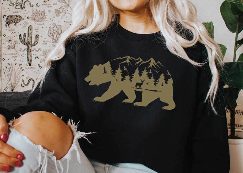 May include: A black sweatshirt with a brown silhouette of a bear with a mountain range and trees inside the bear's body.