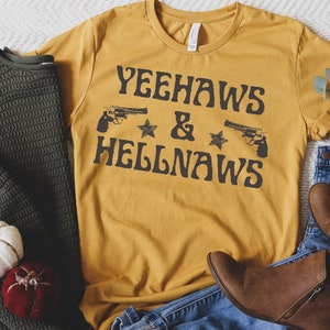 May include: A mustard yellow t-shirt with the text "Yeehaws & Hellnaws" in black. The text is in a retro font and features two stylized pistols and stars.
