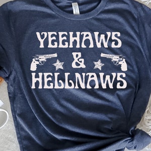 May include: A navy blue t-shirt with the text "Yeehaws & Hellnaws" in white, featuring two stylized pistols and stars.
