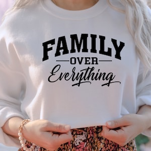 May include: White sweatshirt with black text that reads "FAMILY OVER EVERYTHING" in a bold, collegiate font.