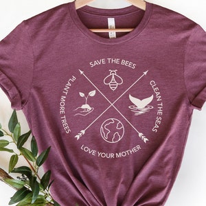 Może przedstawiać: Bordowy t-shirt z białym nadrukiem graficznym. Grafika przedstawia pszczołę, kiełek, ogon wieloryba i globus z tekstem "Save the Bees", "Plant More Trees", "Clean the Seas" i "Love Your Mother".