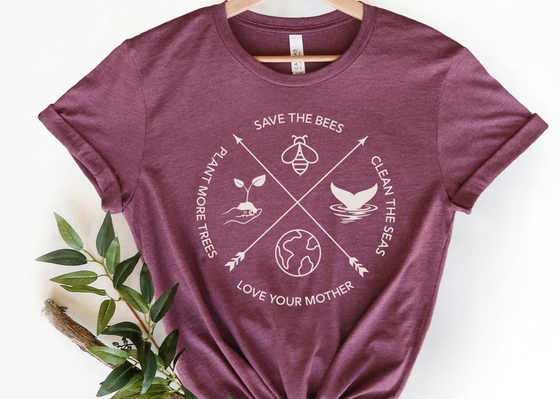 Może przedstawiać: Bordowy t-shirt z białym nadrukiem graficznym. Grafika przedstawia pszczołę, kiełek, ogon wieloryba i globus z tekstem "Save the Bees", "Plant More Trees", "Clean the Seas" i "Love Your Mother".