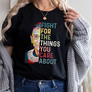 May include: A black t-shirt with a colorful portrait of Ruth Bader Ginsburg and the text "Fight for the things you care about".